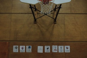Posters demonstrating seven of the 10 learner profile attributes are taped to a gym wall beneath a basketball hoop.